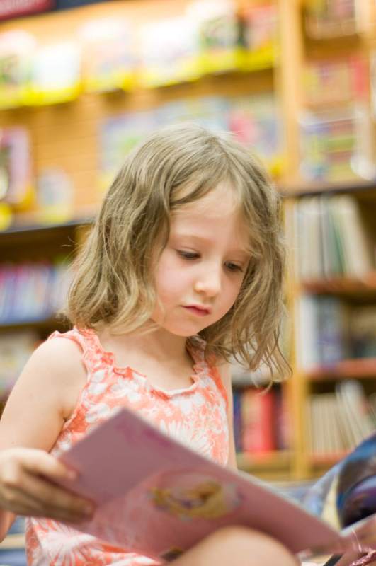 Read at home? Child reading book in school library